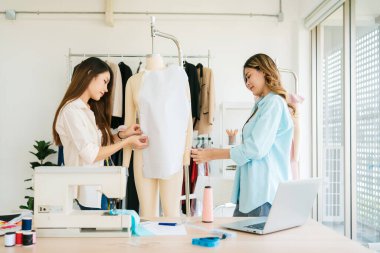 Asyalı kadın moda tasarımcısı ya da terzi kesik kağıt kumaş kalıplarını hazırlamaya yardım ediyor. Atölye terzi atölyesinde çalışan ve yeni moda koleksiyonları tasarlayan bir terzi..