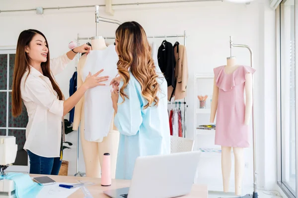 Asyalı kadın moda tasarımcısı ya da terzi kesik kağıt kumaş kalıplarını hazırlamaya yardım ediyor. Atölye terzi atölyesinde çalışan ve yeni moda koleksiyonları tasarlayan bir terzi..