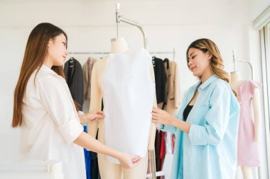 Asyalı kadın moda tasarımcısı ya da terzi kesik kağıt kumaş kalıplarını hazırlamaya yardım ediyor. Atölye terzi atölyesinde çalışan ve yeni moda koleksiyonları tasarlayan bir terzi..