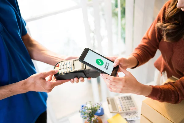 stock image Woman paying bill through smartphone using contactless payment technology. Satisfied customer paying through mobile phone using NFC technology. Closeup hands of mobile payment at mobile handheld POS.