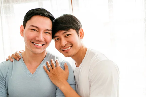 Young happy gay couple in love, proposing and marriage surprise show a wedding ring in the living room at home. Gay men proposal engagement concept. Surprised partner is very happy. Relationship goal.
