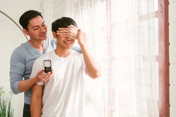 若い幸せなゲイのカップルは 自宅のリビングルームで結婚指輪との結婚式の驚きを提案しています ゲイ男性の婚約の概念を提案 驚くべきパートナーは非常に満足しています 関係目標 — ストック写真