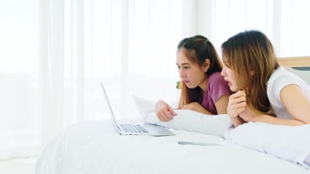 快乐的亚洲女性夫妇一起躺在床上 用笔记本电脑在网上购物 带着微笑和欢笑 女性在社交网络 聊天或上网购物时使用的工具 — 图库视频影像