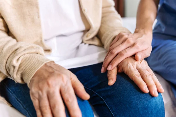 Close-up senior Asian woman hand with her caregiver helping hands, Caregiver visit at home. Home health care and nursing home concept.