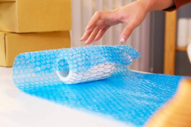 Paketi göndermeden önce kırılgan bir ürün için hava kabarcıklı bir vazo hazırlayan Asyalı kadın. Online mağazasından alışveriş yapan bir müşteriye göndermeye hazır. İnternetten alışveriş kavramı.
