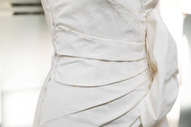 Tailor's textile female mannequin with black lines covered with canvas fabric pattern and draping for dressmakers working and designing new fashion collections in an atelier tailor workshop.