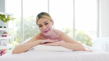 Beyaz çarşaflı ve sağlık merkezli Asya lüks spa salonundaki masaj yataklarına uzanmış genç bir kadın terapistten masaj bekliyor. Spa salonu konsepti