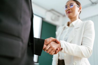 Asyalı iş kadını iş adamı ile tokalaşması, iş birliklerinin takım çalışması ve başarılı pazarlıklar için kazanımlar. İki işadamı iş anlaşmalarını kutlamak için ortaklarıyla tokalaşıyor..