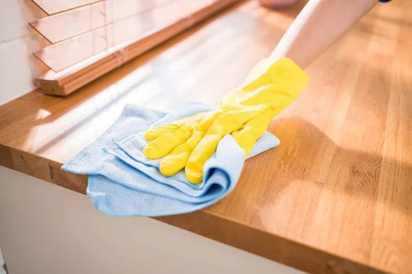 身穿黄色橡胶手套 用抹布擦拭家中厨房顶部木制柜台的亚洲妇女清洁服务机构的专业手 打扫房间 打扫房间 图库照片