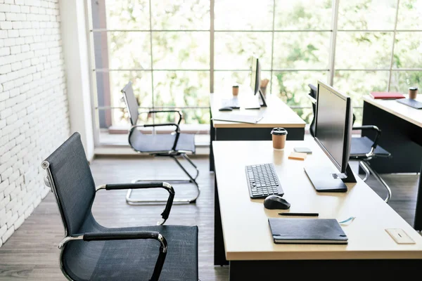 在现代工作空间的桌子上 配备了显示器 笔记本 钢笔和纸杯咖啡等现代化的个人办公桌办公室 带有复制空间的图像 图库图片