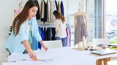 Asyalı kadın moda tasarımcısı ya da terzi kesik kağıt kumaş kalıplarını hazırlamaya yardım ediyor. Atölye terzi atölyesinde çalışan ve yeni moda koleksiyonları tasarlayan bir terzi..