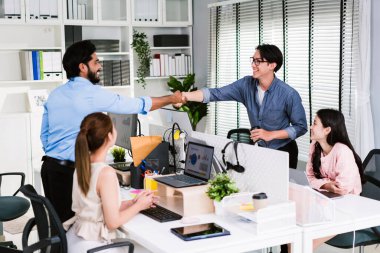 Neşeli Asyalı iş ortakları takım çalışmasının bir sembolü olarak gülümseyerek tokalaşıyorlar. Ofiste çeşitlilik konusunda çok ırklı iş arkadaşları var. İşbirliği kavramı.