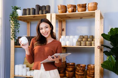 Asyalı güzel bir kadın evde canlı yayında el yapımı vazo satıyor. Genç çekici kız satmadan önce stok ve mal stoğunu kontrol ediyor. Uzak satın alma ve satın alma kavramı.