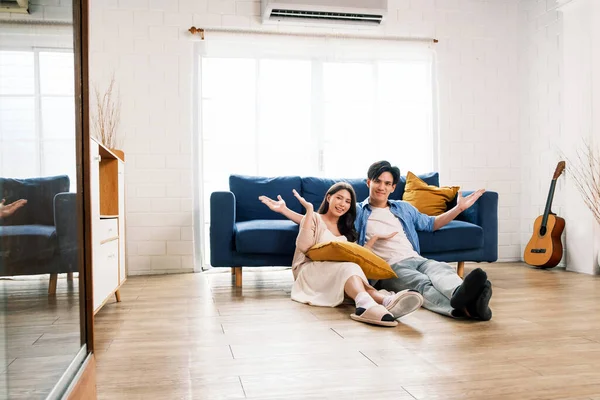 Attractive new marriage man and woman sit on the floor together and feel happy in the living room at the new home. A family spends quality time together after moving into a new home.