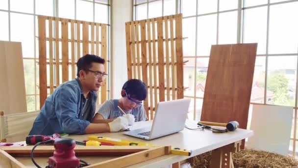 Wesoły Azjatycki Stolarz Omawia Uczy Syna Instrumentach Budowlanych Laptopie Pracowni — Wideo stockowe