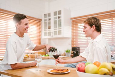 Beyaz, eşcinsel, çekici bir çift. Mutfakta birlikte kırmızı şarap içip eğleniyorlar. Homoseksüellik, eşcinsel ilişkiler, LGBT, eşcinsel partner ve romantik konsept.