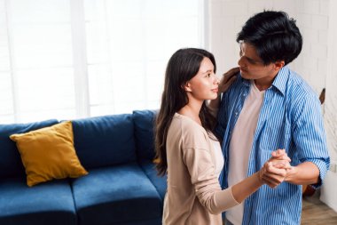 Çekici genç Asyalı çiftler dairenin oturma odasında romantik bir dans etmekten hoşlanırlar. Bir aile yeni bir eve taşındıktan sonra birlikte kaliteli zaman geçirir. Kopyalama alanı olan resim.