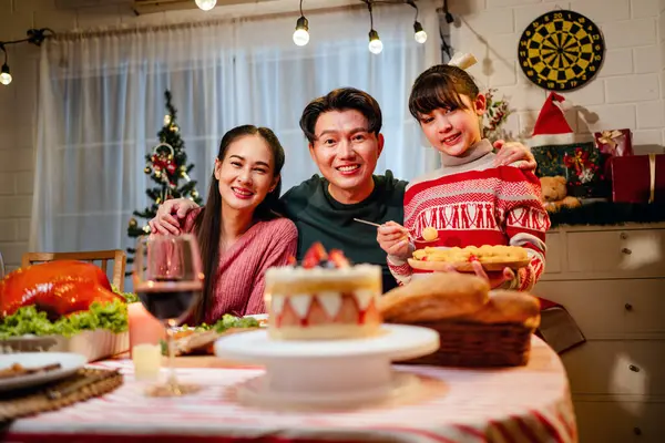 Happy and Cheerful group of extended Asian family and daughter smiling during Christmas dinner at home. Celebration holiday together. Family gatherings and reunions. Focus on young Asian family.