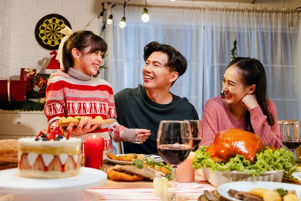 Happy and Cheerful group of extended Asian family talking and smiling during Christmas dinner at home. Celebration holiday together. Family gatherings and reunions. Focus on young Asian Family