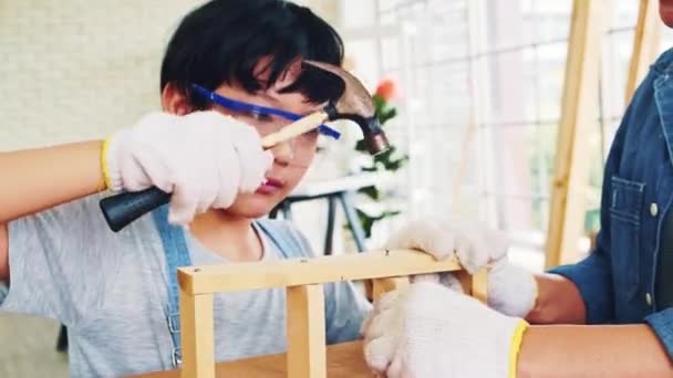 快乐的亚洲父亲和儿子是一名木工和木匠 父亲教他的儿子一起小心地在木板上钉钉子 在家庭作坊工作室工作的木工 — 图库视频影像