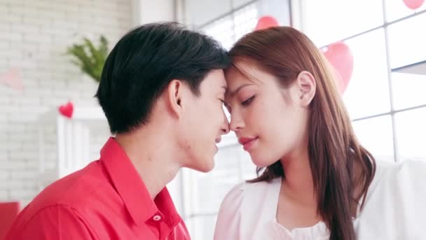 年轻的亚洲浪漫快乐夫妻触摸额头 微笑着闭上双眼 享受温馨浪漫的时刻 并在客厅里分享温馨的感觉 情人节庆祝活动 — 图库视频影像