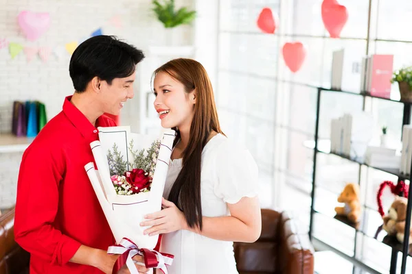 一位年轻的亚洲男人在他的女朋友的结婚周年纪念日那天送给她一束玫瑰花和一束鲜花 让她很吃惊 亚洲女人喜欢收到男朋友的花束 情人节庆祝活动 图库照片