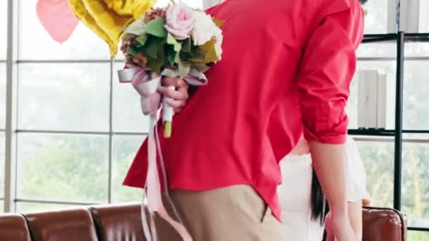 アジアの若い男性は 自宅で彼女の記念日のためにバラと花束を与えることによって 彼女のガールフレンドを驚かせました アジアの女性は 彼女のボーイフレンドから花束を受け取るのが好きです バレンタインデーのお祝い — ストック動画
