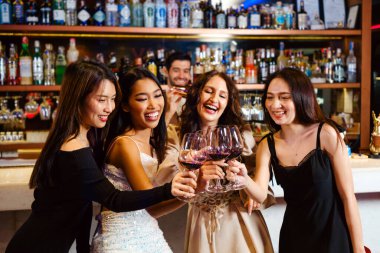 Gençler bir partiyi kutlar, içer, dans eder, gece disko kulübünde eğlenirken içki içerler. Arkadaşlık ve gece hayatı kavramı. Mutlu genç kadınlar şık bir barda eğleniyorlar..