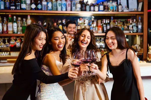 Gençler bir partiyi kutlar, içer, dans eder, gece disko kulübünde eğlenirken içki içerler. Arkadaşlık ve gece hayatı kavramı. Mutlu genç kadınlar şık bir barda eğleniyorlar..