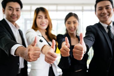 Kameraya başparmaklarını kaldırmış çeşitli iş adamlarından oluşan bir gruba yaklaş. İyi bir seçim önerisi. Asyalı iş adamlarının çeşitliliği olumlu yanıt veriyor.