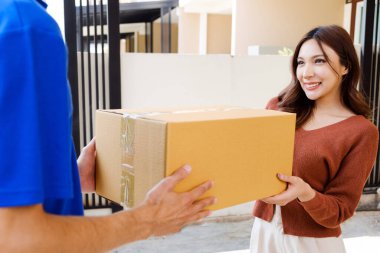 Beyaz adam, üniformalı kurye, Asyalı müşterilere paket teslimatı yapıyor. Kadın, ev girişinin önünde el ele veriyor. Ev paketi teslimat hizmeti kavramı.