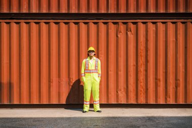 Asyalı mühendis konteynır deposunda duruyor ve konteynırları kontrol ediyor. Nakliye ve uluslararası mal ithalat-ihracatı. Lojistik operasyon kavramı. Fotoğraf alanı kopyala.