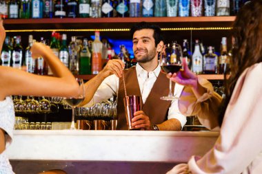 Kafkasyalı profesyonel barmen ya da barmen kadınlar için bir kokteyl hazırlıyor. Çekici barmen, içki malzemelerini kokteyl karıştırıcı ve gülümsemeyle karıştırır. Gece kulübü restoranında barmen..