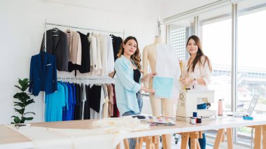 Asyalı kadın moda tasarımcısı ya da terzi kesik kağıt kumaş kalıplarını hazırlamaya yardım ediyor. Atölye terzi atölyesinde çalışan ve yeni moda koleksiyonları tasarlayan bir terzi..