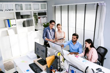 Çeşitli bir ekiple bilgisayar üzerinde işbirliği yapan, takım çalışması ve profesyonellik sergileyen modern bir ofis. Bir toplantıda iş adamlarının çeşitliliği.