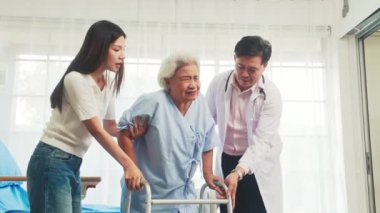 Bakıcı ve aile bireyi, yaşlı bir kadına bir yürüteçle yardım eder, sağlık hizmetlerinde sıcaklık, destek ve bağlantı taşır..