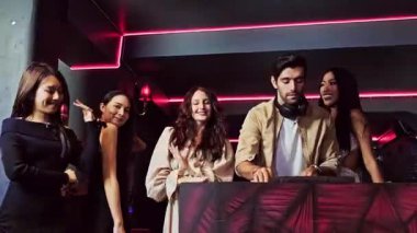 Dj ile dans eden enerjik bir grup kadın gece partisinden zevk alıyor. Genç kadınlar gece kulübünde dans eder. Gece hayatı, disko dansı ve kızların gece partisi konsepti. Eğlenceli müzik festivali. Gerçek zamanlı 4k video