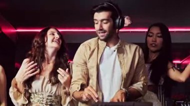 Dj ile dans eden enerjik bir grup kadın gece partisinden zevk alıyor. Genç kadınlar gece kulübünde dans eder. Gece hayatı, disko dansı ve kızların gece partisi konsepti. Eğlenceli müzik festivali. Gerçek zamanlı 4k video