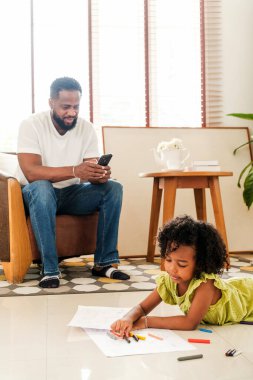 Babası telefonda dinlenirken, kızı da pastel boyalarla resim çiziyor. Evdeki samimi aile bağları, gösterişli ebeveynlik, çocukluk yaratıcılığı, kapalı mekan oyunları ve modern aile hayatı..