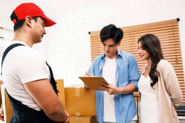 Teslimat işçisi paketleri yeni evlerindeki bir çifte teslim eder. Ev taşıma, taşınma, lojistik, nakliye, ticaret, kurye hizmeti ve çevrimiçi alışveriş konuları için ideal.