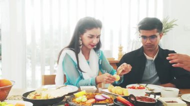 Hint ailesi geleneksel yemekleri birlikte yer, pani puri, biryani ve köri içerir. Etnik giyinmiş bir kadın yemek hazırlar, kültürü, birlikteliği ve mirası kutlar. Gerçek zamanlı 4k video.