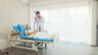 Hastane yatağında yatan yaşlı bir kadın bir doktordan bakım görüyor. Klinik ortamda kıdemli sağlık, sağlık sigortası, hasta iyileştirme ve profesyonel tedavi kavramı. Yavaş çekim 4k video.