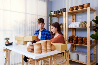 İki genç Kafkasyalı ve Asyalı girişimci küçük iş alanlarında ürün sevkiyatı hazırlıyorlar. Çevrimiçi mağaza sahipleri ecommerce ambalajlama, lojistik ve sipariş tamamlama.