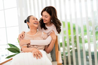 Mutlu anne ve kız, aydınlık bir oturma odasında sıcak bir kucaklaşmayı paylaşıyor. Anneler Günü 'nü kutluyor, kendine bakıyorlar. Huzurlu bir yuvada sevgi, bağlılık ve duygusal refahı yakalıyorlar..