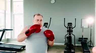Fitness, sağlık ve yağ kaybı için beden eğitiminde kilolu bir adam boks yapıyor. Yaşlılar için aktif yaşlanma, sağlık ve sağlıklı yaşam tarzını kardiyo egzersizleri ve ağırlık yönetimi çabaları yoluyla teşvik eder.