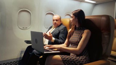 Uçuş sırasında dizüstü bilgisayar kullanan iki havayolu yolcusu, özel bir kabinde kablosuz internet ve inflight eğlence, iş seyahati, üretkenlik ve dijital bağlantı hizmetleri için ideal.