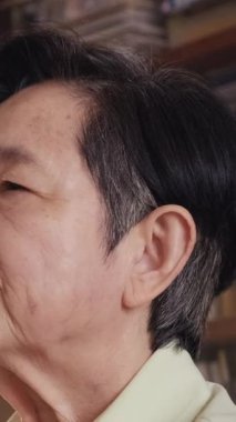 İşitme cihazını düzeltirken üst düzey bir kadının kulağına yakın çekim yaparak, ev ortamında işitme kaybı ve yaşlı bağımsızlığı için günlük asist teknolojinin kullanımını vurguluyor..