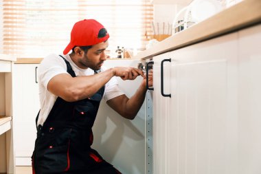 Mutfak dolabını tamir etmeye odaklanmış tamirci evdeki lavabonun altında sergilenen su tesisatı, tamir uzmanlığı, ev bakımı ve emlak bakımı için tamirat desteği..