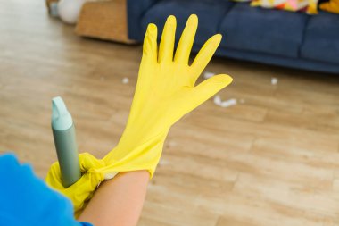 Sarı lastik eldiven giyen, elinde temizlik spreyi tutan ve ev işlerine hazırlanan birinin yakın çekimi. Temizlik, hijyen bakımı ve ev işleri konsepti..