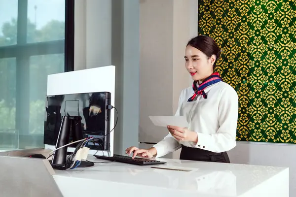 Üniformalı havayolu çalışanları, modern bir gişede uçuş kartı işliyor. Havaalanı ortamında profesyonelliği, müşteri hizmetlerini ve seyahat verimliliğini yakalar.